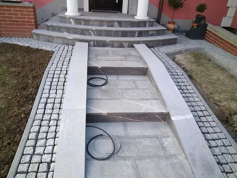 Pot iz kamnitih plošč z robom iz granitnih kock pred vhodom v hišo